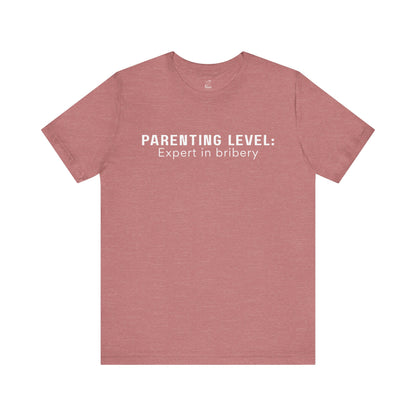 Parenting Humor Shirt | Unisex T-Shirt | Funny Parent Tee | Gift for Moms and Dads | Casual Family Outfit | “Parenting Level: Expert in Bribery”